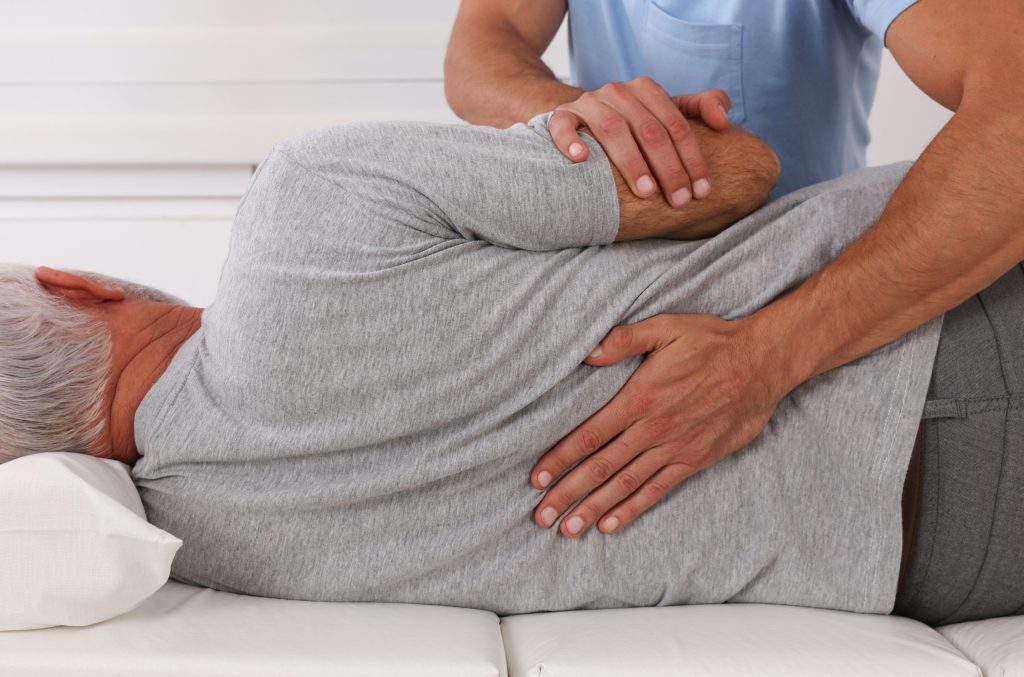 Chiropractor palpating a patient's lower back during a lumbar spine examination.